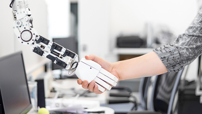 Human shaking hands with a robot arm.